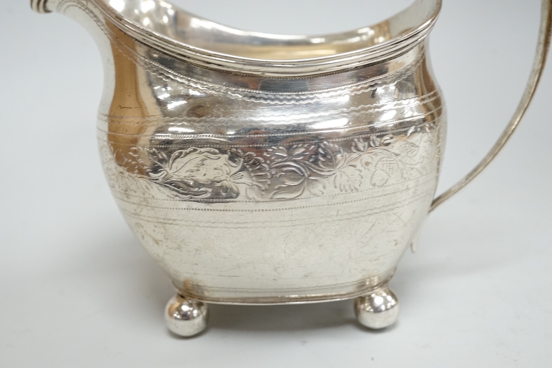 A George III silver cream jug, on four ball feet, London, 1812, 95mm, with engraved foliate band, maker's mark rubbed.